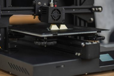 close up view of 3D printer creating plastic model on blurred background clipart