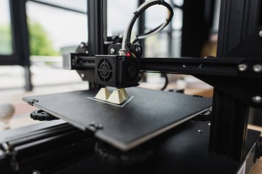 3D printer creating plastic model on table in modern office