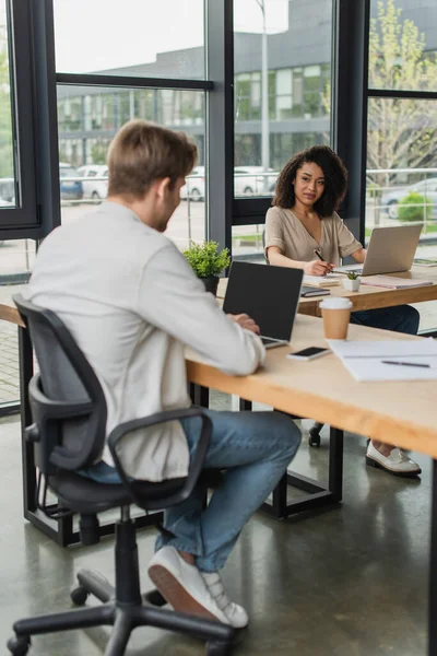 Colegas Interraciales Sentados Escritorios Trabajando Con Computadoras Portátiles Espacio Abierto —  Fotos de Stock