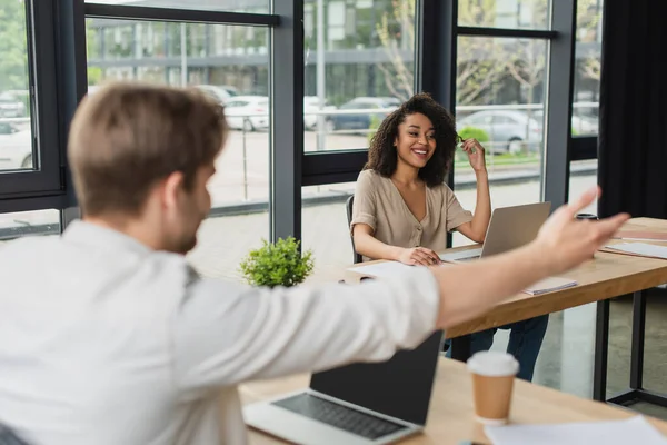 Positive Interracial Colleagues Sitting Desks Laptops Gesturing Hands Modern Open — Stockfoto