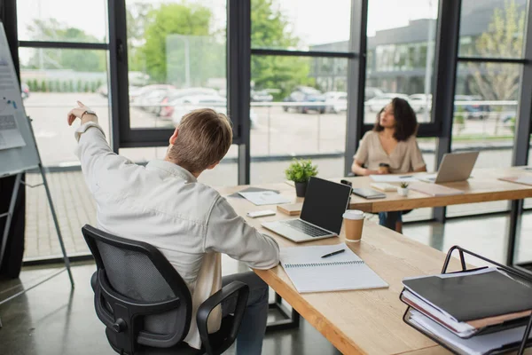 Giovane Uomo Che Punta Con Dito Flip Chart Vicino Sfocato — Foto Stock