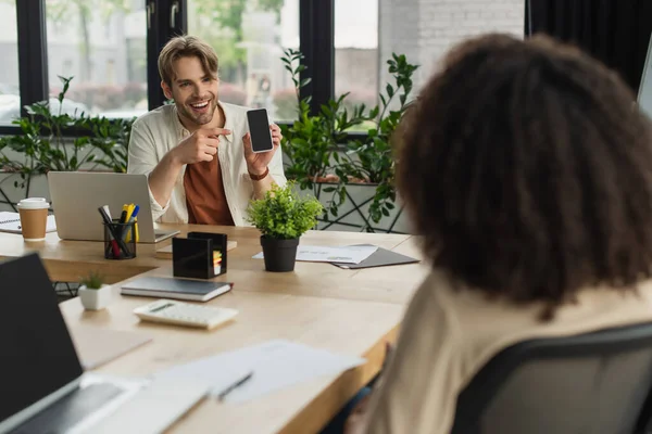 Smiling Young Man Pointing Finger Smartphone Screen Blurred African American — Stockfoto