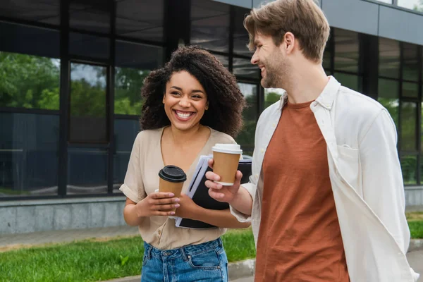 Smiling Young Interracial Couple Paper Coffee Cups Folder Documents Walking — Stockfoto