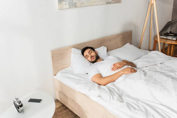 Ung Man Sover Nära Mobiltelefon Och Väckarklocka Nattduksbordet — Stockfoto