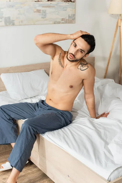 Hombre Sin Camisa Pantalones Mirando Cámara Mientras Está Sentado Cama — Foto de Stock