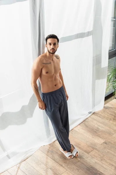 Hombre Sin Camisa Pantalones Zapatillas Mirando Cámara Cerca Ventana — Foto de Stock