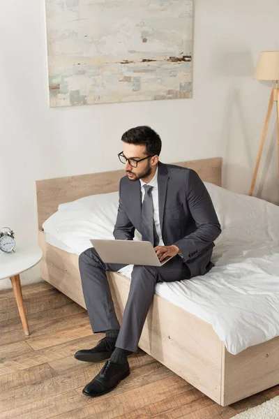 Joven Hombre Negocios Usando Ordenador Portátil Mientras Está Sentado Cama — Foto de Stock