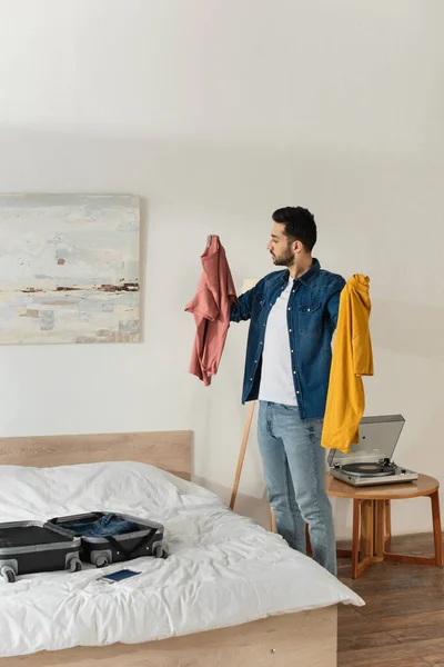 Vista Lateral Homem Segurando Camisetas Perto Mala Passaporte Cama — Fotografia de Stock