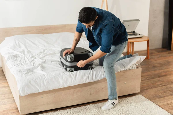 Young Man Zipping Suitcase Bed Home — Stock Photo, Image