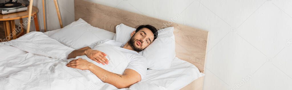 Young man in white t-shirt sleeping on bed, banner 