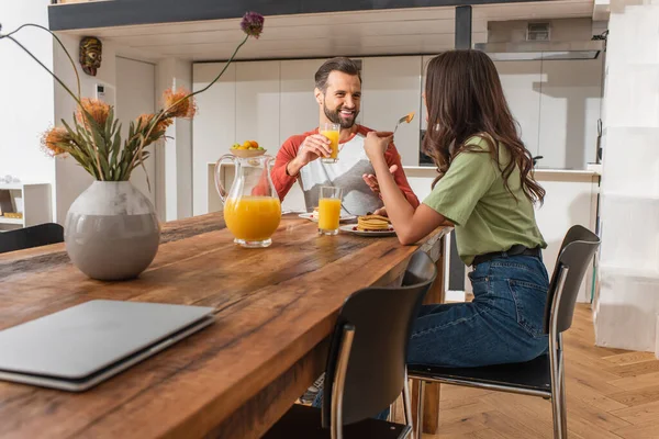 Vrolijke Man Met Sinaasappelsap Gesprek Met Vriendin Buurt Van Pannenkoeken — Stockfoto