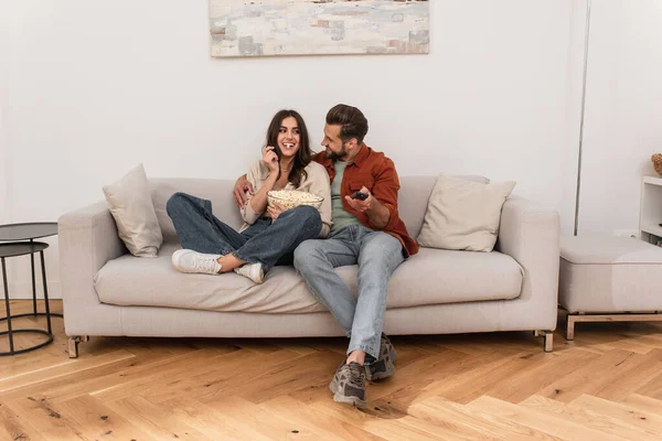 Smiling Man Remote Controller Looking Girlfriend Eating Popcorn Home — Stock Photo, Image