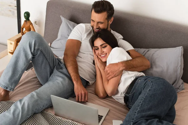 Casal Alegre Olhando Para Laptop Abraçando Cama — Fotografia de Stock