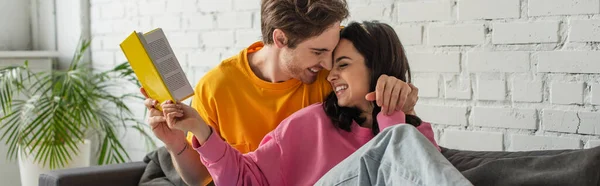 Feliz Jovem Casal Abraçando Com Livro Mãos Sala Estar Banner — Fotografia de Stock