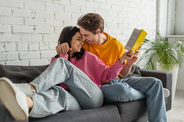 Happy Young Couple Hugging Holding Book Living Room — Stock Photo, Image
