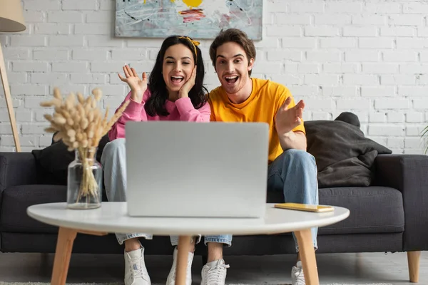 Positive Young Couple Sitting Couch Open Mouths Waving Hands While — Stock Photo, Image