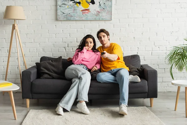 Young Man Pointing Remote Controller Camera Hugging Girlfriend Living Room — Stock Photo, Image