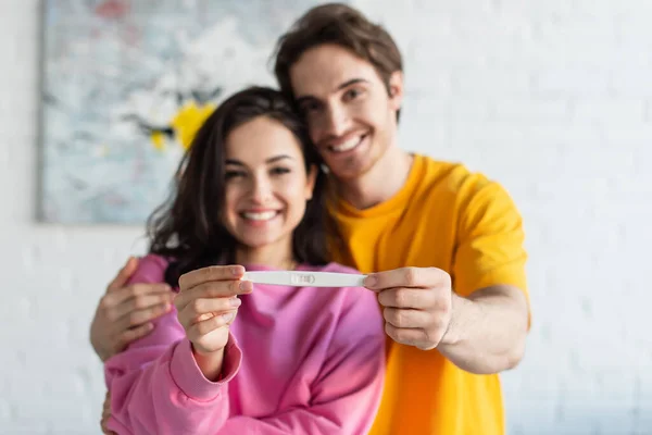 Prueba Embarazo Manos Borrosa Sonriente Pareja Joven Casa — Foto de Stock
