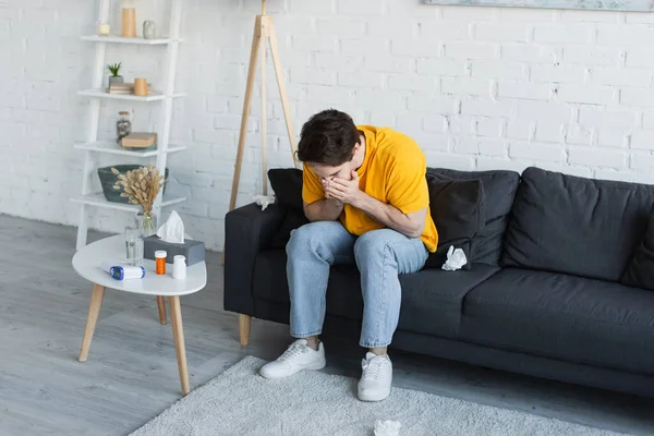 Zieke Jongeman Zitten Bank Niezen Met Handen Bedekken Gezicht Thuis — Stockfoto