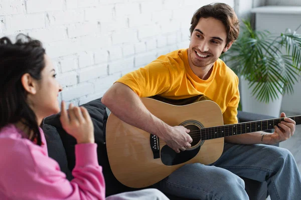 Sonriente Joven Sentado Sofá Con Guitarra Acústica Cerca Novia Casa — Foto de Stock