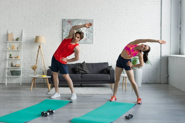 在家里锻炼前 让年轻夫妇穿着运动服在健身垫旁边锻炼 — 图库照片
