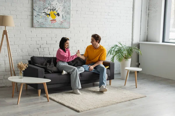 Playful Young Couple Sitting Couch Touching Hands Living Room — Stock Photo, Image