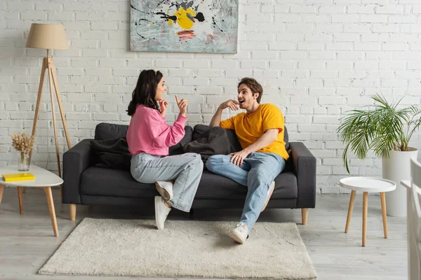 Smiling Young Couple Sitting Couch Gesturing Hands Living Room — Stock Photo, Image