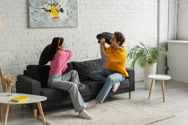 Smiling Young Couple Fighting Pillows Couch Living Room — Stock Photo, Image