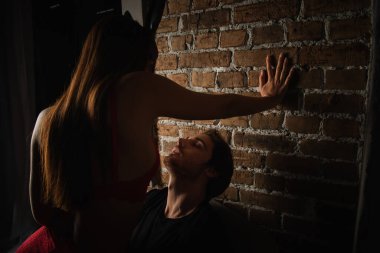 hot woman in bunny ears making love with young man near brick wall in darkness clipart