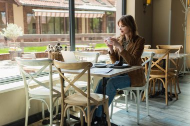 Cafe 'de tatlı ve laptopun yanında fincanı tutan serbest çalışan biri. 