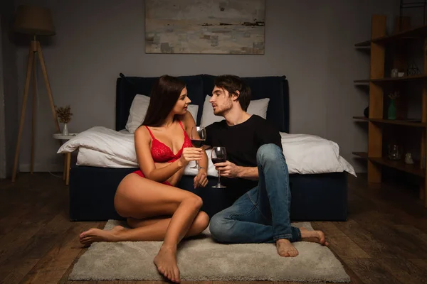 Genç Aşıklar Kırmızı Şarap Kadehleriyle Yatak Odasında Yerde Oturuyorlar — Stok fotoğraf