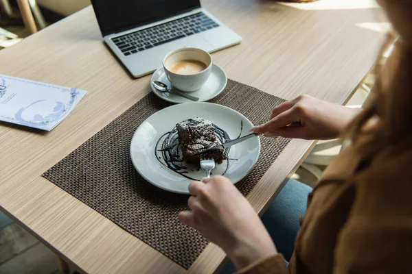 Cropped View Woman Cutting Cake Coffee Laptop Cafe — Stock Photo, Image