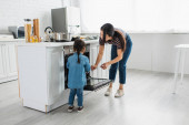 Asijské matka a dítě stojící v blízkosti otevřené trouby v kuchyni 