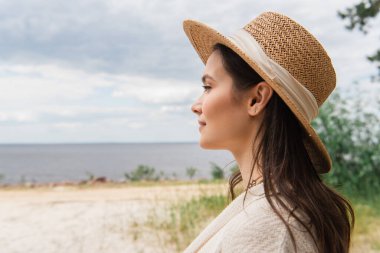 Deniz kenarında güneş şapkalı mutlu bir kadın. 