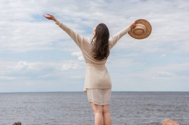 Deniz kenarında uzanmış duran genç bir kadının arka görüntüsü.