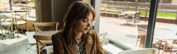 молодая женщина в очках, смотрящая вниз в кафе, баннер