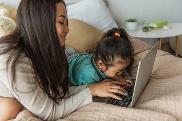 Sorridente Donna Asiatica Utilizzando Laptop Vicino Bambino Camera Letto — Foto Stock