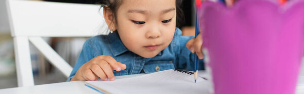 Asian girl drawing on paper at home, banner 