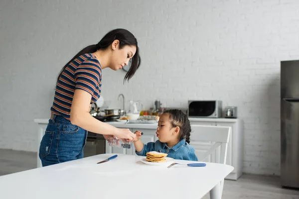 Asiatisk Mamma Håller Blåbär Nära Barn Och Pannkakor Köket — Stockfoto