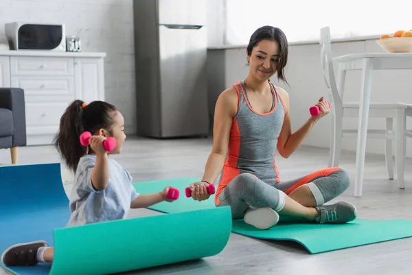 Sorrindo Asiático Esportista Exercitando Com Halteres Perto Criança Tapete Fitness — Fotografia de Stock