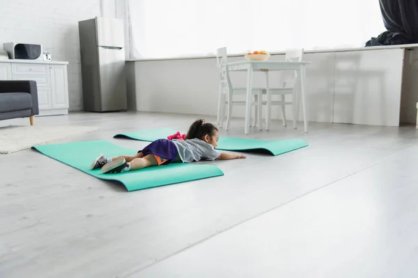 亚洲小孩在家里的哑铃旁躺在健身垫上 — 图库照片