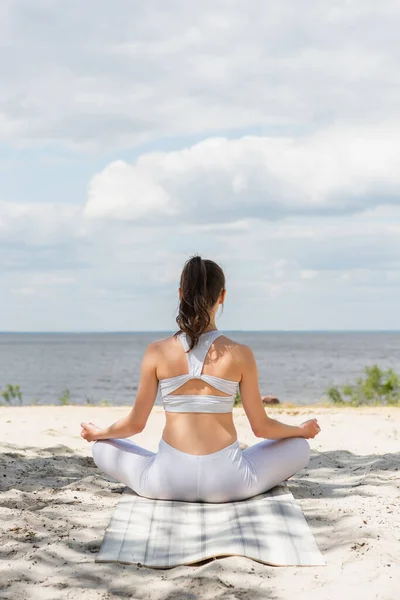 Vista Posterior Mujer Morena Meditando Esterilla Yoga Cerca Del Mar —  Fotos de Stock