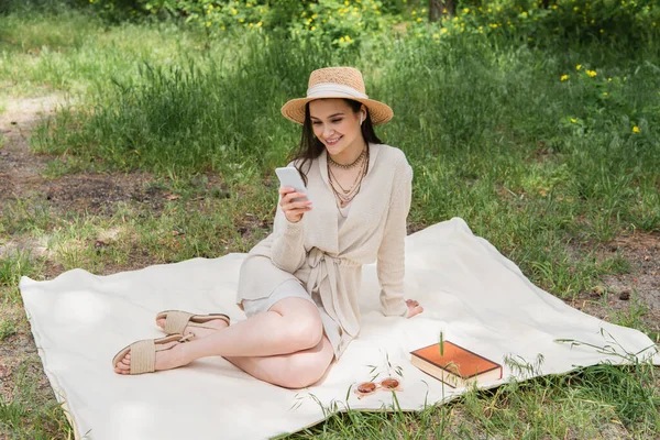 Giovane Donna Sorridente Cappello Paglia Auricolari Wireless Utilizzando Smartphone Mentre — Foto Stock