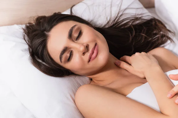 happy young woman with closed eyes lying on pillow