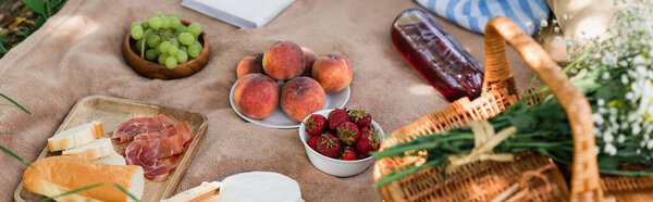 Высокий угол обзора вкусной еды, вина и цветов на одеяле в парке, баннер 