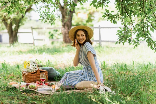 Mulher Chapéu Sol Falando Celular Perto Vinho Comida Flores Parque — Fotografia de Stock