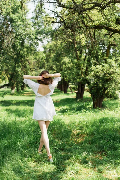 穿着白色衣服在草地上行走的女人的背影 — 图库照片