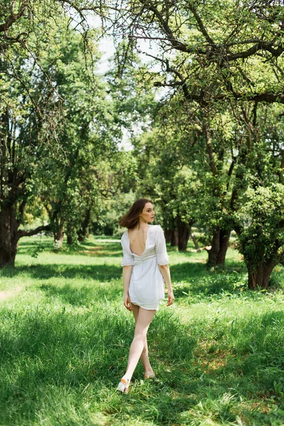 Vista Lateral Jovem Mulher Vestido Branco Andando Grama Parque — Fotografia de Stock