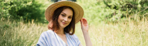 Smiling woman in sun hat looking at camera in park, banner