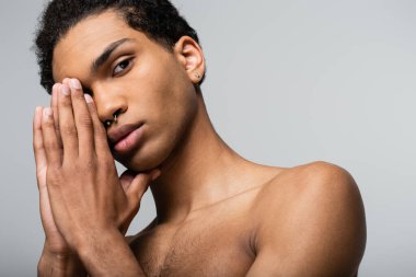 Gri güzellik konseptine izole edilmiş kameraya bakarken yüzüne yakın poz veren Afro-Amerikan bir adam.